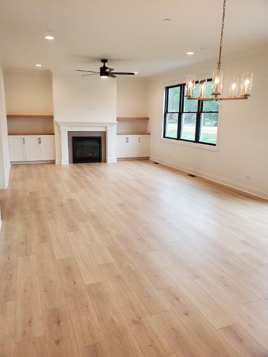 Flooring in a living room with a fireplace and large windows.